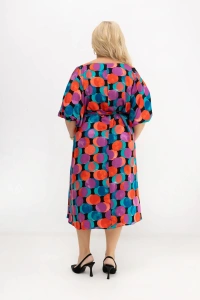 Tył sukienki plus size Arie w kolorowe koła z paskiem prezentuje swobodny fason, prosty krój oraz efektowny wzór na całej powierzchni. Widać długość do kolan i wygodne rękawy zakończone gumką.