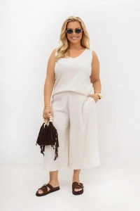 Komplet Nelka ecru PLUS SIZE z topem na szerokich ramiączkach i szerokimi spodniami typu culotte. Stylizacja z plecioną torebką i klapkami – idealna na lato.