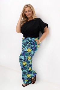 Stylizacja ze spodniami plus size Marisa w turkusowym kolorze z egzotycznym nadrukiem. Model prezentuje szerokie nogawki, wysoki stan i wygodny fason z kieszeniami.
