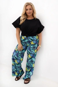 Spodnie damskie plus size Marisa z szerokimi nogawkami i turkusowym owocowym wzorem. Model prezentuje wygodny fason z wysokim stanem, kieszeniami oraz elastyczną gumką w pasie.