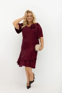 Sukienka Evelyn bordowa Plus Size z odpinaną różą i falbanami. Elegancka sukienka midi na wesele i przyjęcie, z luźnym fasonem, krótkimi rękawami oraz subtelnie połyskującą tkaniną.