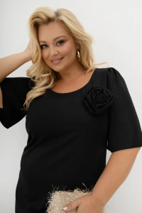 Czarna sukienka Evelyn Plus Size z odpinaną różą i falbanami. Elegancki model midi na wesele, poprawiny, bal i rodzinne uroczystości, z luźniejszym fasonem i dekoracyjnym detalem przy dekolcie.