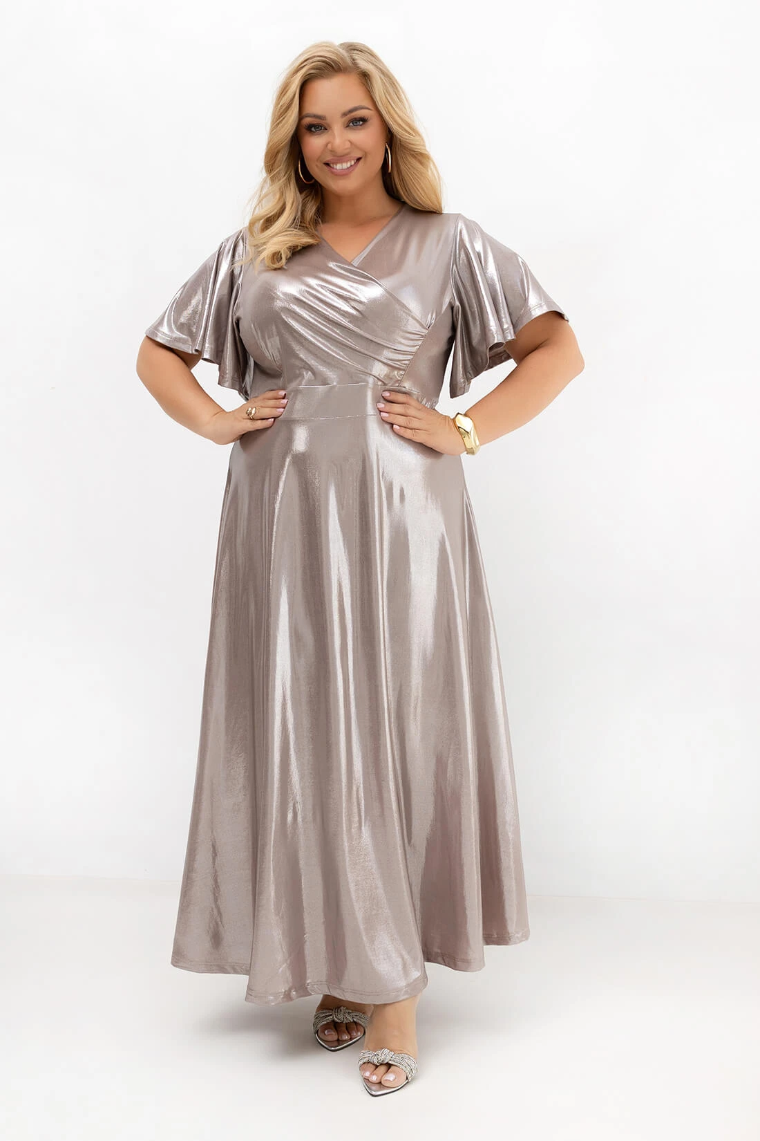 Elegancka sukienka maxi PLUS SIZE w kolorze szampańskim z połyskującej tkaniny. Kopertowy dekolt, szeroki pas i zwiewne rękawy. Idealna sukienka na wesele, bal, studniówkę, komunię i eleganckie przyjęcia.