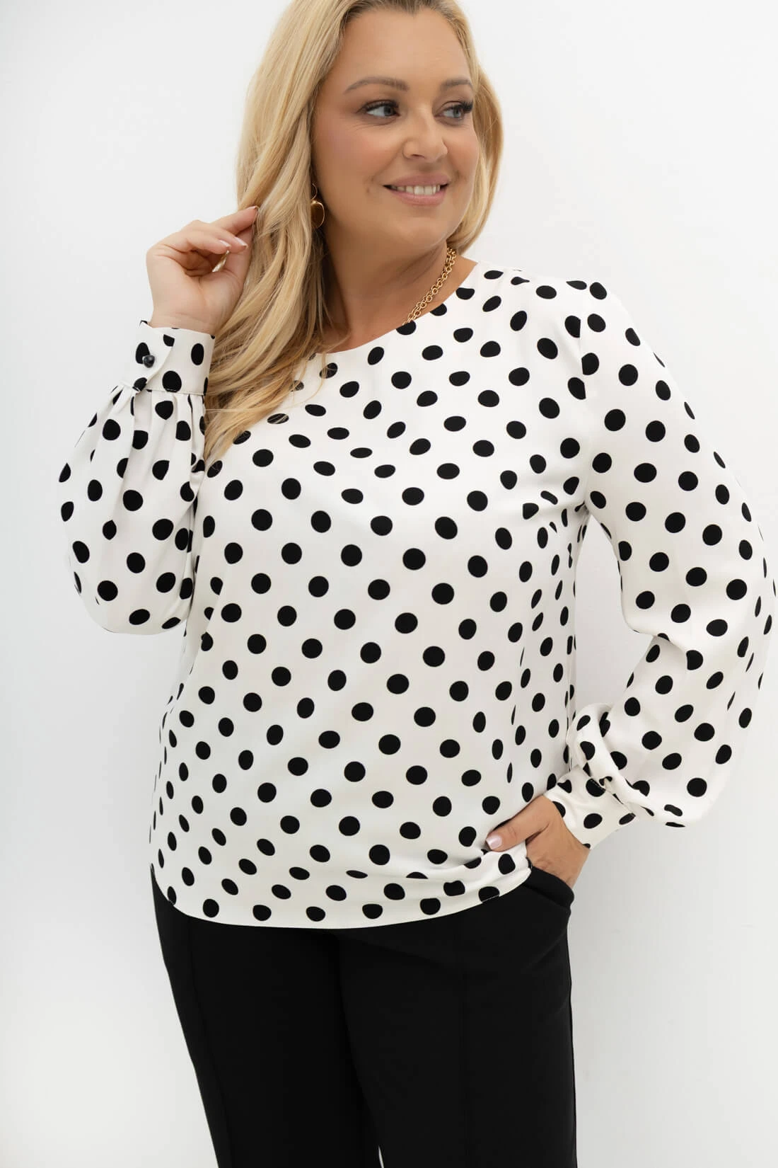 Elegancka bluzka Dot Darling w czarne grochy Plus Size – zbliżenie na fason, dekoracyjne zakładki na rękawach i mankiety.